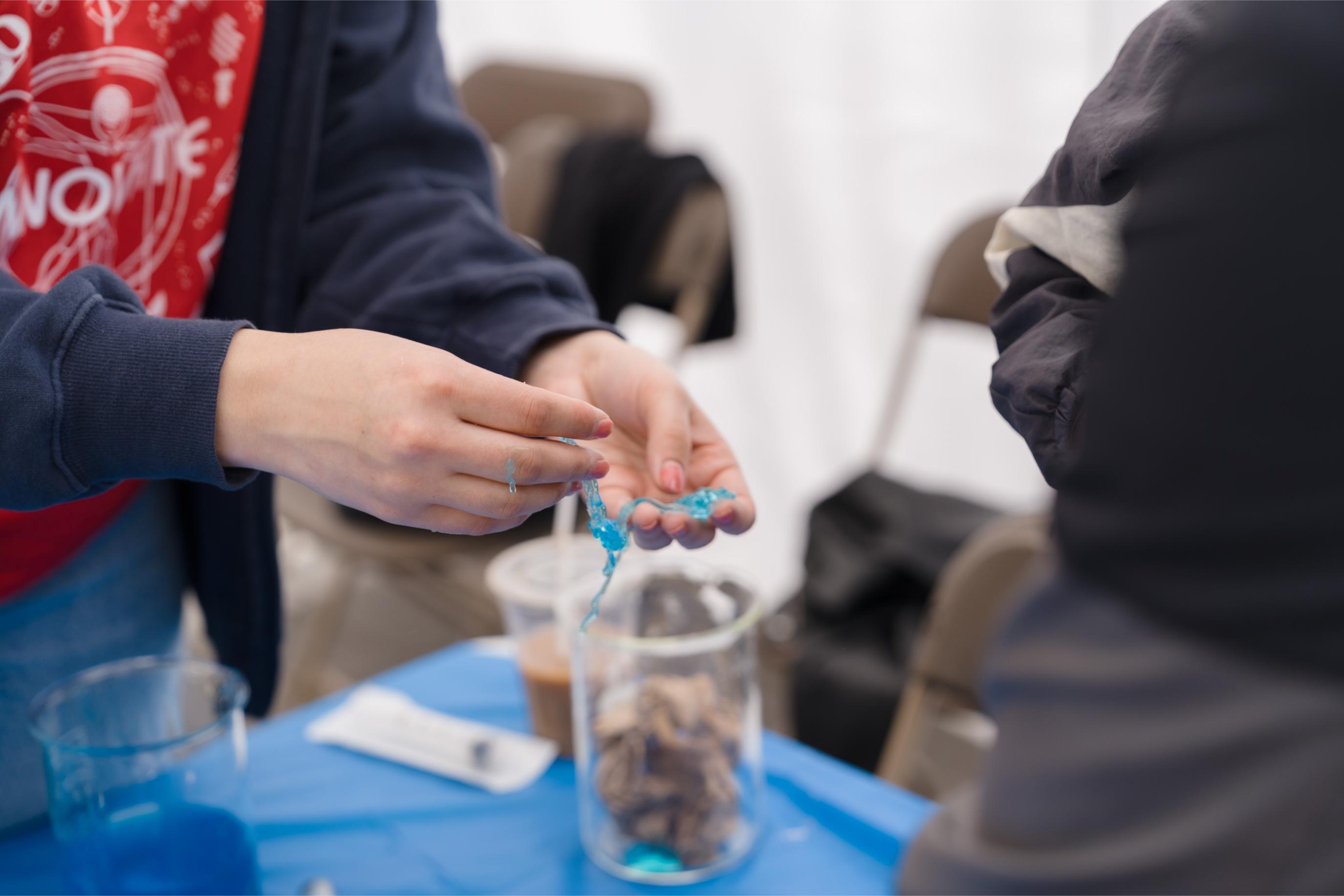 A volunteer holding a blue slime at the Food Science Now Booth.